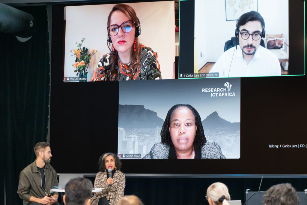 Foto del evento de presentación del reporte enseñando dos personas sobre el escenario en dónde se ve al fondo una proyección de pantalla de zoom con otros tres particpantes.